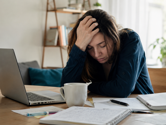 Persona apoyada sobre una mesa con gesto de agotamiento mientras intenta trabajar o estudiar