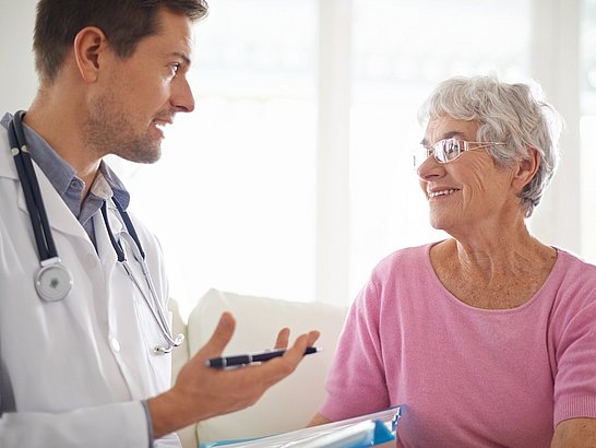 Un médico y una paciente mayor revisando una historia clínica juntos en un consultorio moderno, mostrando atención personalizada.