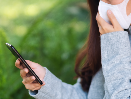 Mujer con mascarilla FFP2 mirando su móvil con una app de niveles de polen