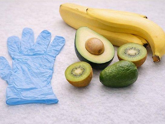 Guantes de látex junto a frutas tropicales (aguacate, plátano, kiwi)