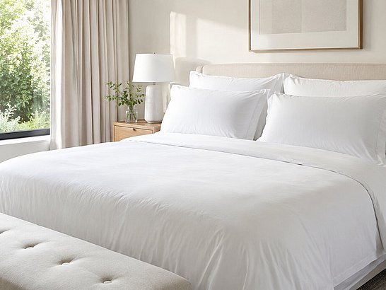 Dormitorio limpio con cama perfectamente hecha, ropa de cama blanca y luz natural entrando por una ventana Dormitorio limpio con cama perfectamente hecha, ropa de cama blanca y luz natural entrando por una ventana