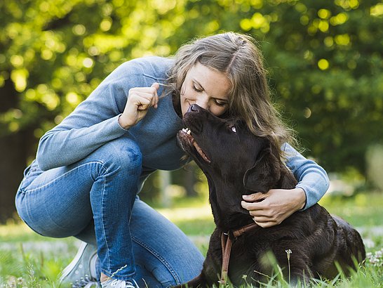 Mujer besando a su perro en el jardín